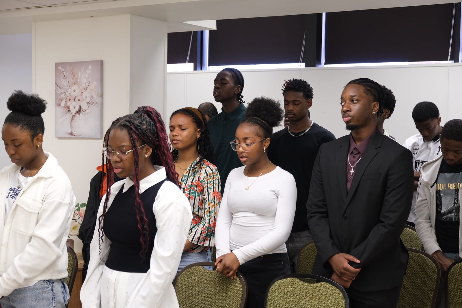 Des jeunes de l’église debout, recueillis, pendant le culte